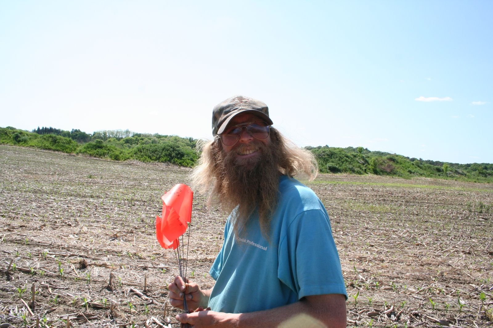 David Moyer in a plowed field during a pedestrian survey, holding a pin flag